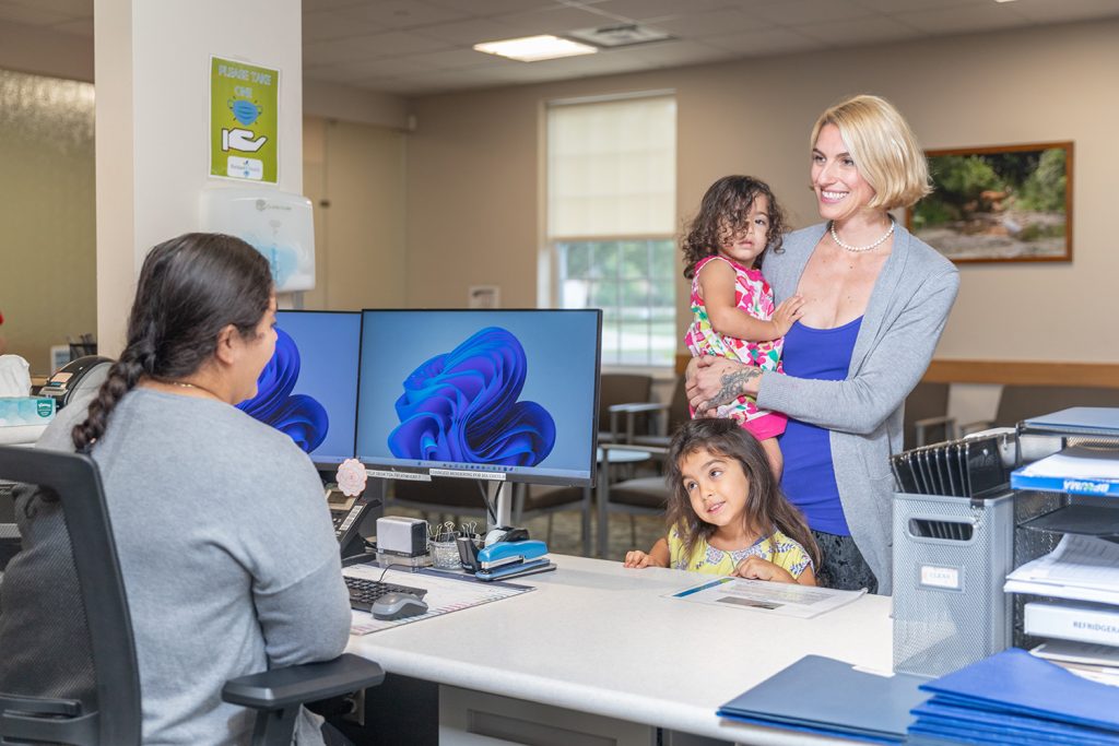 mother and children checking in at Packard Health Main front desk